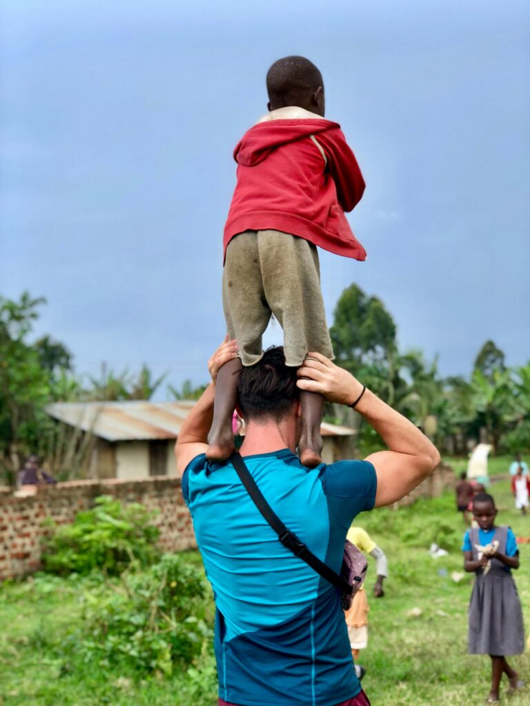 A man carries a child on his shoulders in a village in Fort Portal, Uganda.